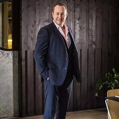 A man in a suit standing in front of a restaurant located in Brisbane.