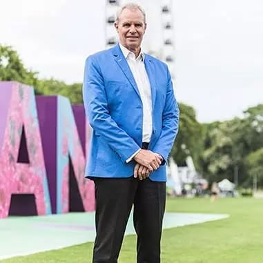 A man in a blue jacket standing in front of a large sign advertising Brisbane lawyers.