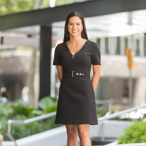 Zoe standing on a sidewalk in a black dress.