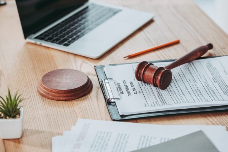 A judge gavel sits on a desk next to a laptop.