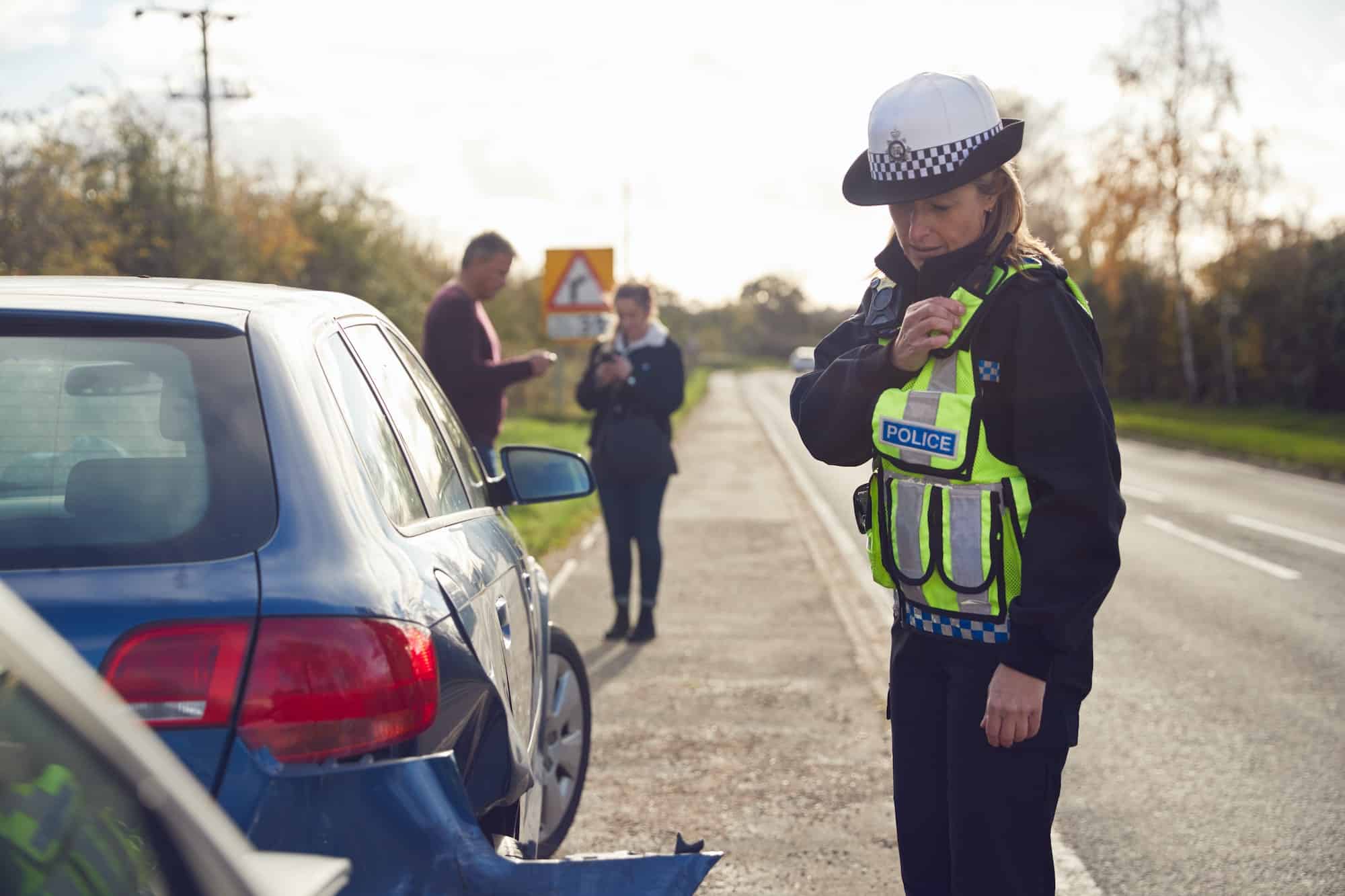 A police officer standing next to a car after a crash.