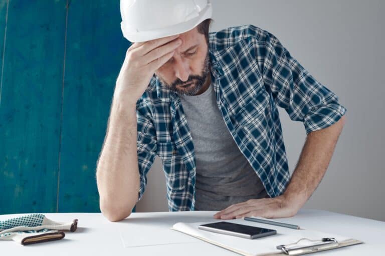 A man wearing a hard hat is sitting at a desk.