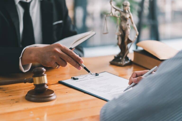 A lawyer signing a document with a gavel.