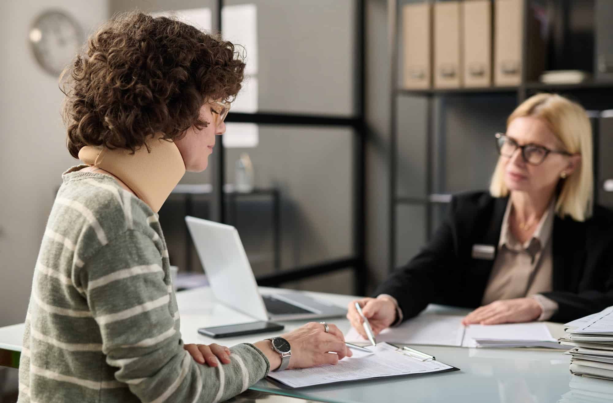 A woman is sitting at a desk and talking to a lawyer.