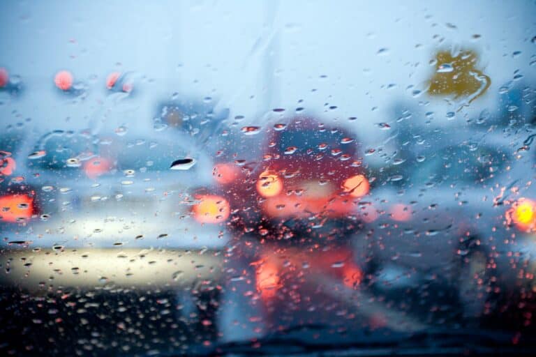 Car driving in a rain storm with blurred red lights