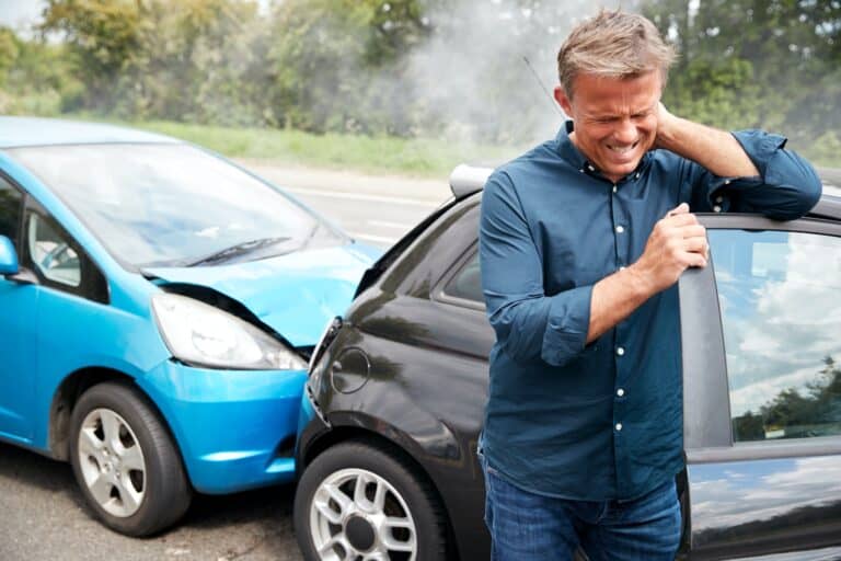 Mature Male Motorist With Whiplash Injury In Car Crash Getting Out Of Vehicle